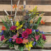 Colorful mixed floral arrangement with roses and calla lilies in a container
