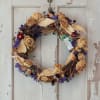 Dried floral wreath with tan roses and purple accents on a white door