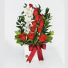 Red roses and white orchids arranged in a white vase with a red ribbon