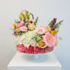 Medium Cake arrangement filled  with carnations, pompons and top with roses