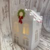 White paper house-shaped gift box with a holiday wreath decoration
