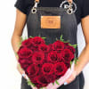 Heart-shaped box of red roses held by a person in an apron