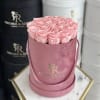 Pink roses arranged in a round velvet hat box with ribbon