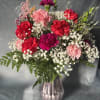 Bouquet of pink and red carnations with baby's breath in a glass vase