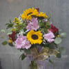 Bouquet of sunflowers, pink alstroemeria, and red roses in a glass vase