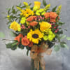 Bouquet of yellow sunflowers and orange roses in a glass vase