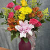A bright and cheerful small vase featuring warm orange lilies, lively orange