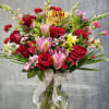 Bouquet of red roses and pink lilies in a glass vase with a birthday topper