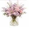 Pink and lavender flowers arranged in a clear glass vase