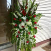 Standing floral spray with red roses and white lilies on a metal easel