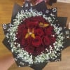 Bouquet of red roses with white baby's breath in black patterned wrap