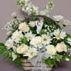 White flowers arranged in a basket with a ribbon and angel figurine
