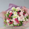 Bouquet of pink roses, white blooms, and bright pink flowers wrapped in pink paper