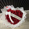 Heart-shaped bouquet of red roses wrapped in white paper with a ribbon