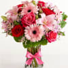 Bouquet of pink lilies, red roses, and pink gerbera daisies in a glass vase