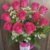 Hot pink roses arranged in a pink tumbler with small white filler flowers