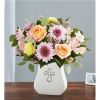 Mixed bouquet of roses and daisies in a white vase with a cross