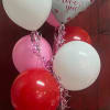 Heart-shaped love-you balloon with several pink, red, and white balloons