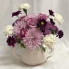 Pink and purple flowers arranged in a speckled white mug