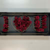 Red roses arranged to spell "I ♥ U" in a black tray