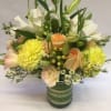 Mixed bouquet of white and peach flowers in a green glass vase