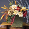 Autumn floral arrangement with cream and red blooms in a green container