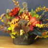 Autumn floral arrangement with pumpkins in a metal container