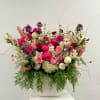 Large arrangement of pink and white mixed flowers in a white ceramic vase