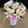 Bouquet of pale yellow roses, pink gerbera daisies, and white lilies wrapped in pink paper