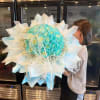 Large turquoise rose bouquet wrapped in white paper with a ribbon