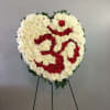 Heart-shaped floral wreath of white and red flowers on a stand