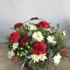 Basket arrangement of red and white carnations with greenery and berries