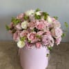 Pink and white roses arranged in a round pastel pink box