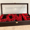 Red roses arranged in a black display box with a clear lid