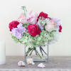 Bouquet of pink and white roses with lavender flowers in a square glass vase