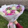 Handheld bouquet of pink and white roses wrapped in white paper