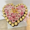 Heart-shaped arrangement of pink roses and gold-wrapped chocolates with a birthday topper