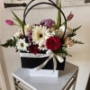 Mixed arrangement of roses, gerbera daisies, tulips and mums in a black handbag-style box with ribbon bow