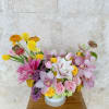 Mixed bouquet of pink, yellow, and white flowers in a round white box