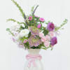 Pink and white mixed flower arrangement in a white vase with a pink bow
