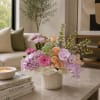 Pastel floral arrangement in a white vase with orchids, roses, and chrysanthemums