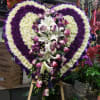 Heart-shaped floral standing spray with white, purple, and pink flowers