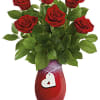Red roses in a red vase with a white heart tag