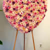Heart-shaped rose arrangement on an easel in pink, peach, and purple tones