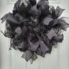 Black mesh wreath with gray ribbon loops on a white door