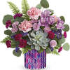 Mixed pink and purple bouquet in a patterned vase with a succulent centerpiece