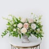 Blush and white roses arranged in a gray pedestal vase