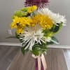 Bouquet of white, yellow, green, and purple chrysanthemum blooms in a pink vase