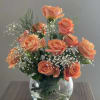 Peach roses arranged in a clear glass vase with baby's breath