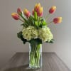Pink tulips arranged with white hydrangeas in a clear glass vase